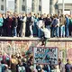 Viele Menschen drängen sich auf und vor der Berliner Mauer.
